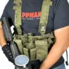 Man wearing tactical vest and holding gun.